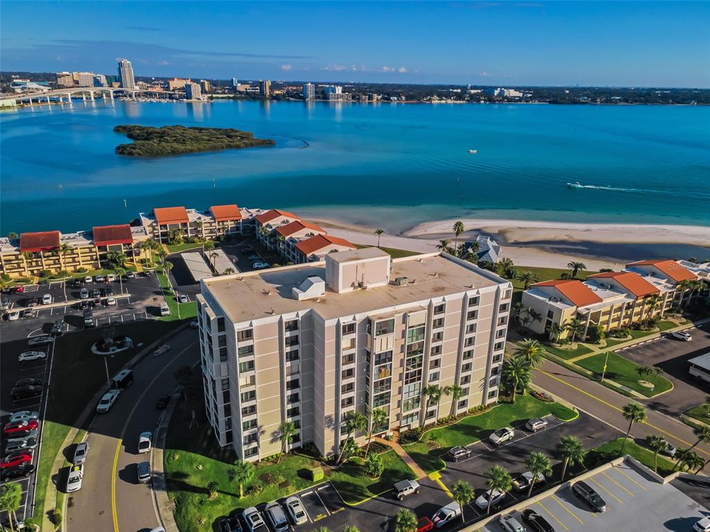 An aerial view of a multi-story apartment building situated near a beach and bay — 855 BAYWAY BOULEVARD UNIT 708, CLEARWATER BEACH, FL