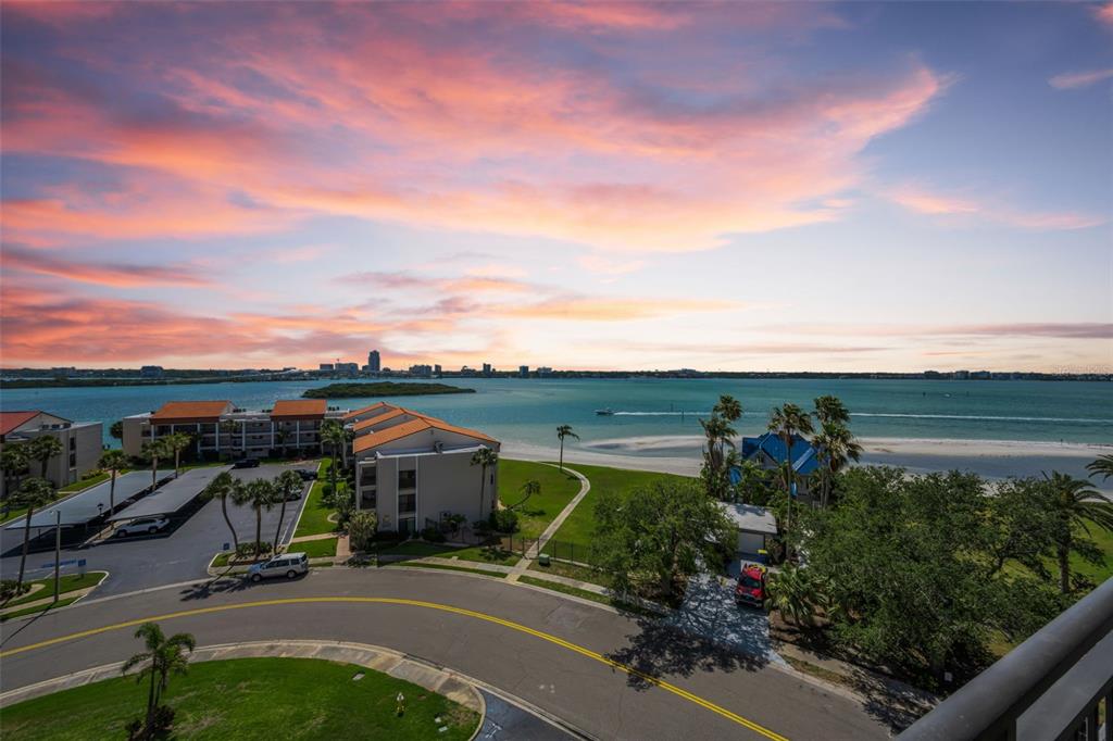 An elevated view of a coastal residential complex with a parking lot and waterfront beach — 855 BAYWAY BOULEVARD UNIT 708, CLEARWATER BEACH, FL