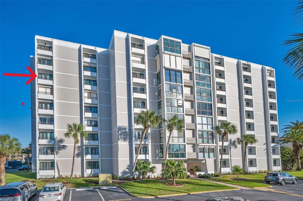 A multi-story residential building with a red arrow pointing to a balcony on the left — 855 BAYWAY BOULEVARD UNIT 708, CLEARWATER BEACH, FL