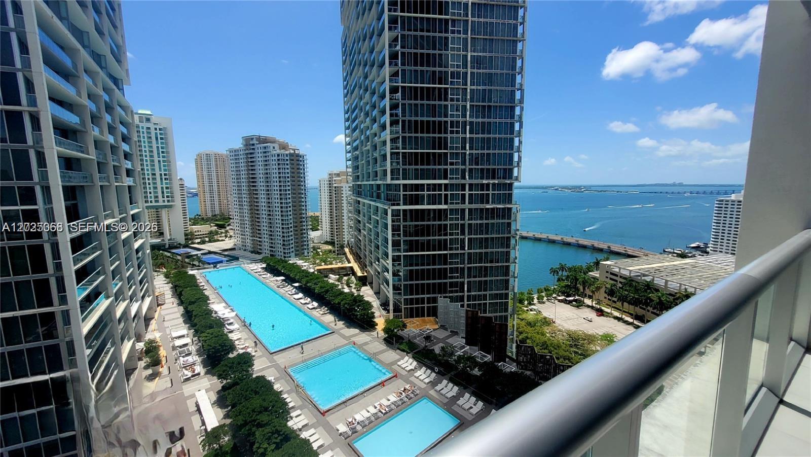 A high-angle view shows multiple swimming pools between tall residential towers overlooking the ocean — 485 Brickell Ave # 2311, Miami FL 33131, MIAMI, FL