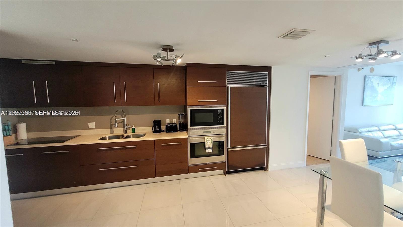 A modern kitchen features dark wood cabinetry, stainless steel appliances, and light tile flooring — 485 Brickell Ave # 2311, Miami FL 33131, MIAMI, FL