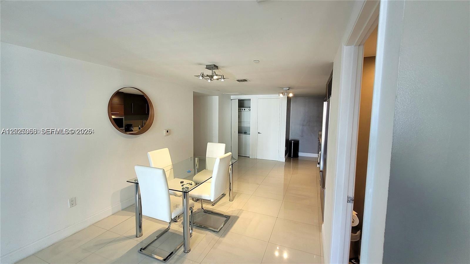 A dining area features a glass table, white chairs, and tile flooring — 485 Brickell Ave # 2311, Miami FL 33131, MIAMI, FL