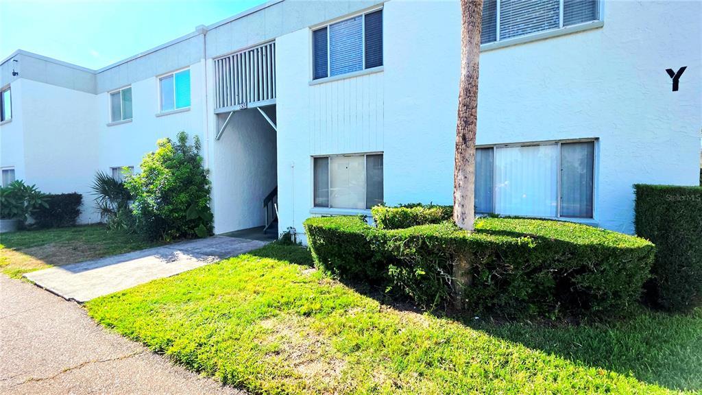 A two-story white apartment building features a covered entryway and a manicured hedge — 851 N KEENE ROAD UNIT Y7, CLEARWATER, FL