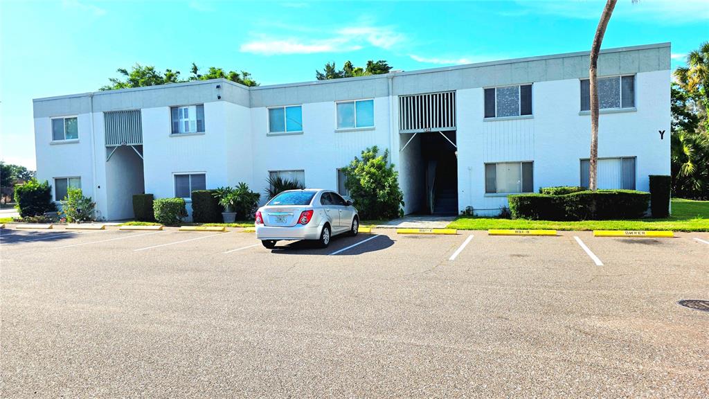 A two-story white apartment building with a parking lot in the foreground — 851 N KEENE ROAD UNIT Y7, CLEARWATER, FL