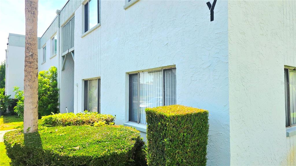 A light-colored stucco apartment building exterior features a large letter Y and manicured hedges — 851 N KEENE ROAD UNIT Y7, CLEARWATER, FL