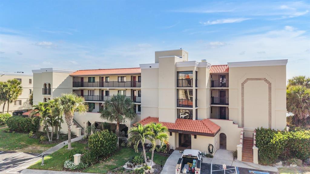 An exterior view of a multi-story apartment building with a red tile roof and balconies — 7435 BAYSHORE DRIVE UNIT 303, TREASURE ISLAND, FL