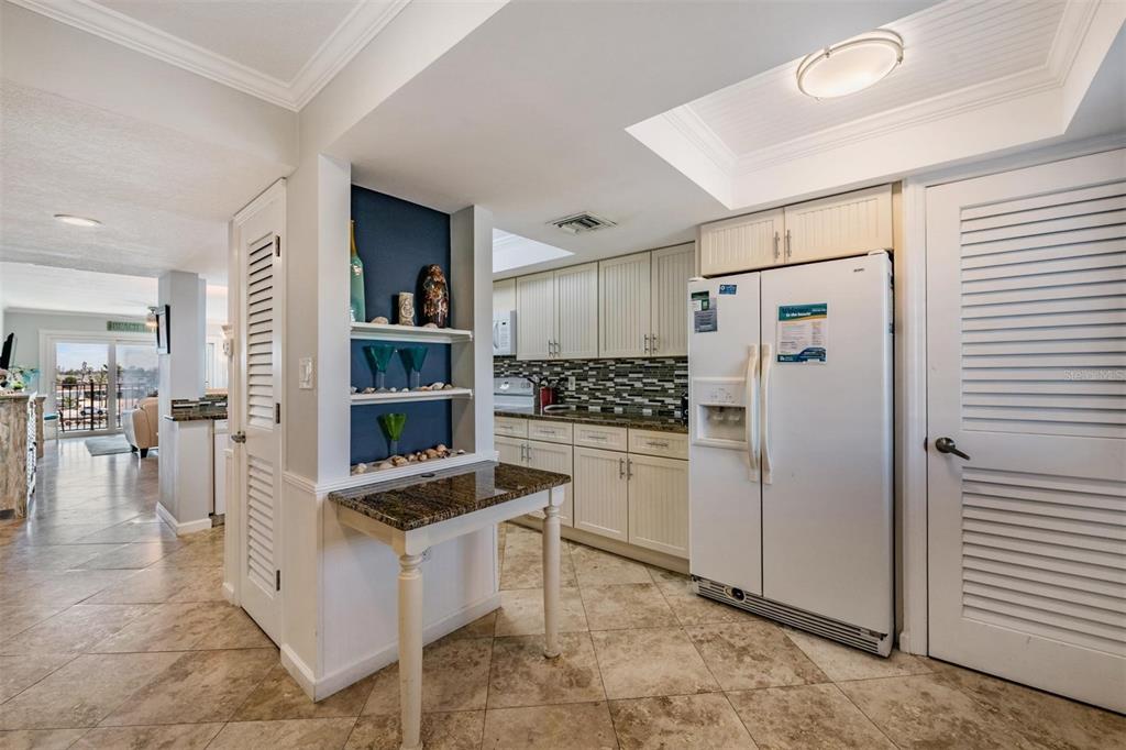 A kitchen features white cabinets, a granite-topped breakfast bar, and a white refrigerator — 7435 BAYSHORE DRIVE UNIT 303, TREASURE ISLAND, FL