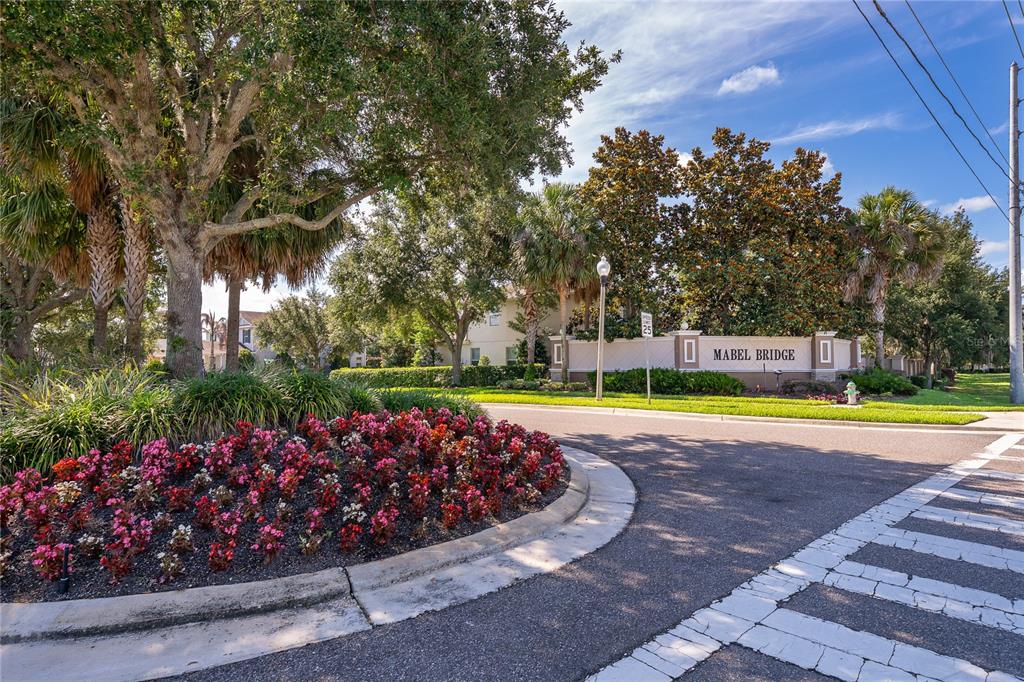 A street-level view of the Mabel Bridge community entrance with a landscaped flower bed — 11437 WAKEWORTH STREET, ORLANDO, FL