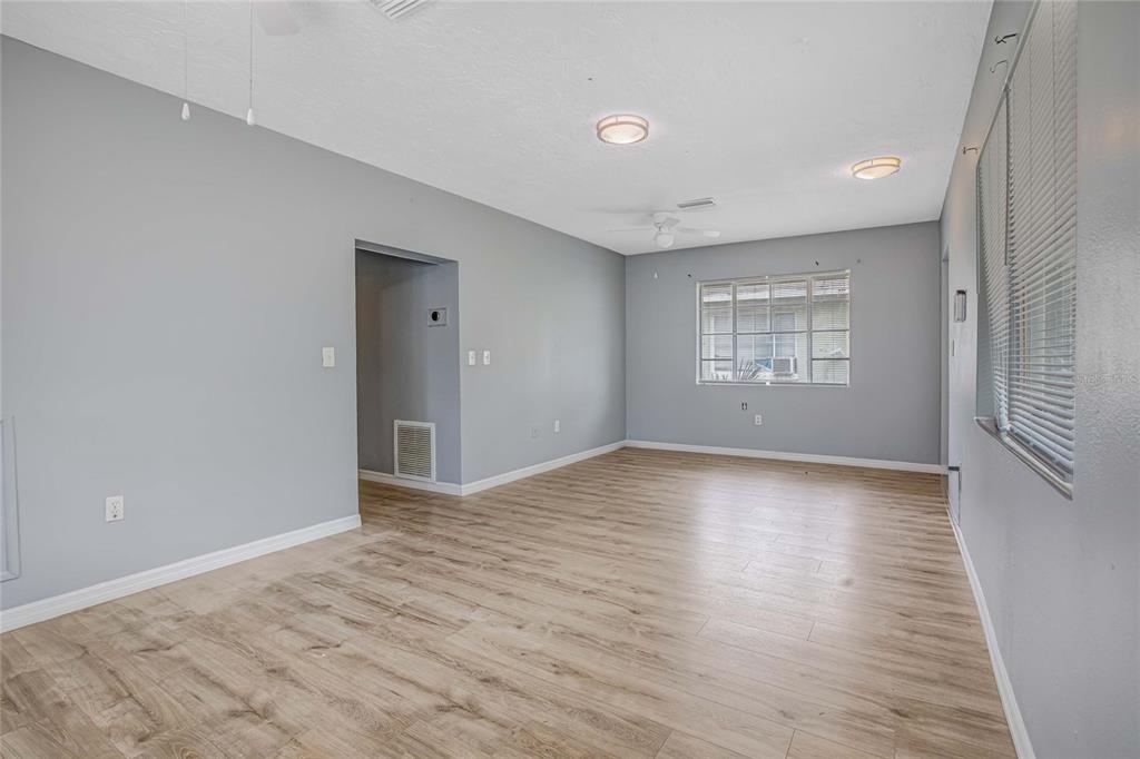 An empty room with light wood-look flooring, gray walls, a ceiling fan, and a window — 1416 19TH AVENUE W, BRADENTON, FL