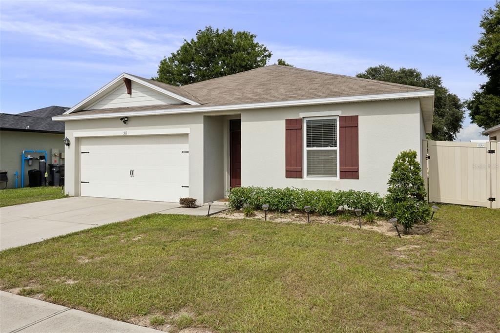 A single-story house with a beige stucco exterior, a two-car garage, and brown shutters — 511 JACKS WAY, DAVENPORT, FL