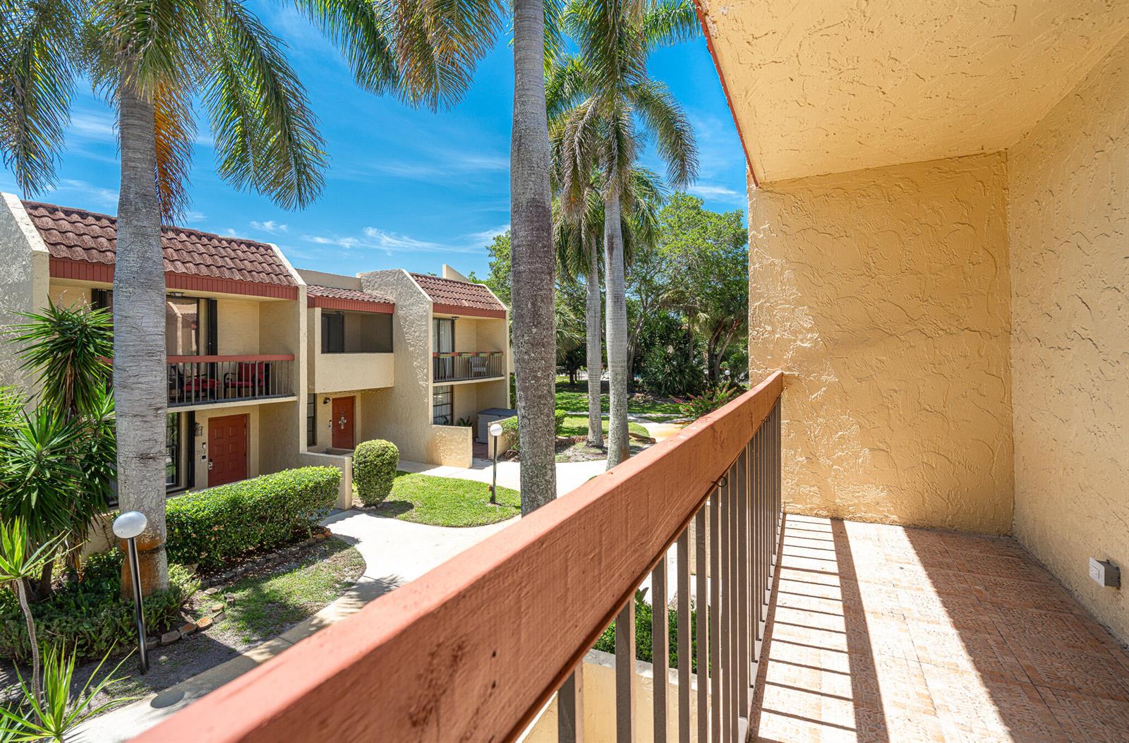 A view from a second-story balcony overlooking a courtyard with palm trees and apartment buildings — 769 SE 1st Way # 85, Deerfield Beach FL 33441, DEERFIELD BEACH, FL