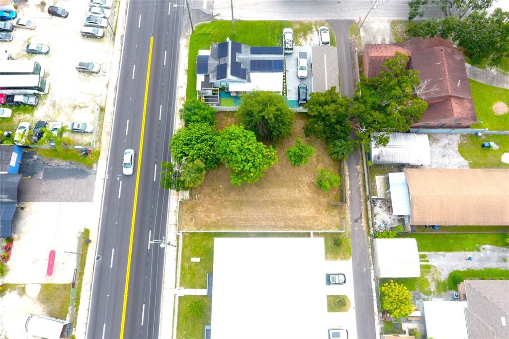 An aerial view shows a vacant lot situated between a house and a commercial building — 2606 W COLUMBUS DRIVE, TAMPA, FL