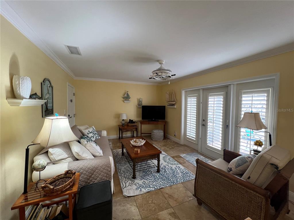 A living room with yellow walls, tile flooring, a sofa, a coffee table, and glass doors — 5164 BEACH DRIVE SE UNIT B furnished, ST PETERSBURG, FL