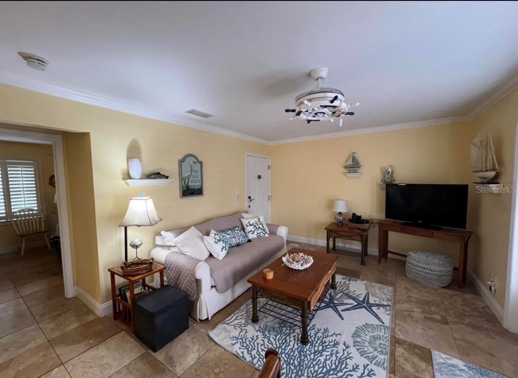 A living room with yellow walls, tile flooring, a sofa, and nautical-themed decor — 5164 BEACH DRIVE SE UNIT B furnished, ST PETERSBURG, FL