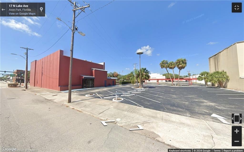 A red commercial building stands next to a paved parking lot with palm trees — 2 W Main Street, FL 33825, FL