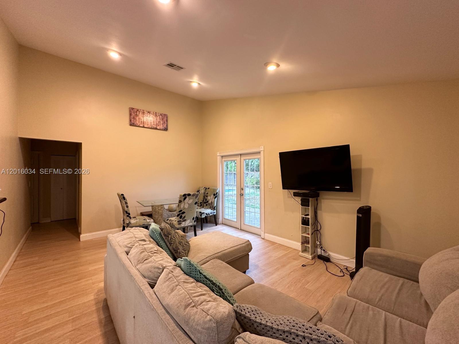 A kitchen with wood cabinets and stainless steel appliances opens into a spacious living area — 11143 E Model Cir E, Boca Raton FL 33428, BOCA RATON, FL