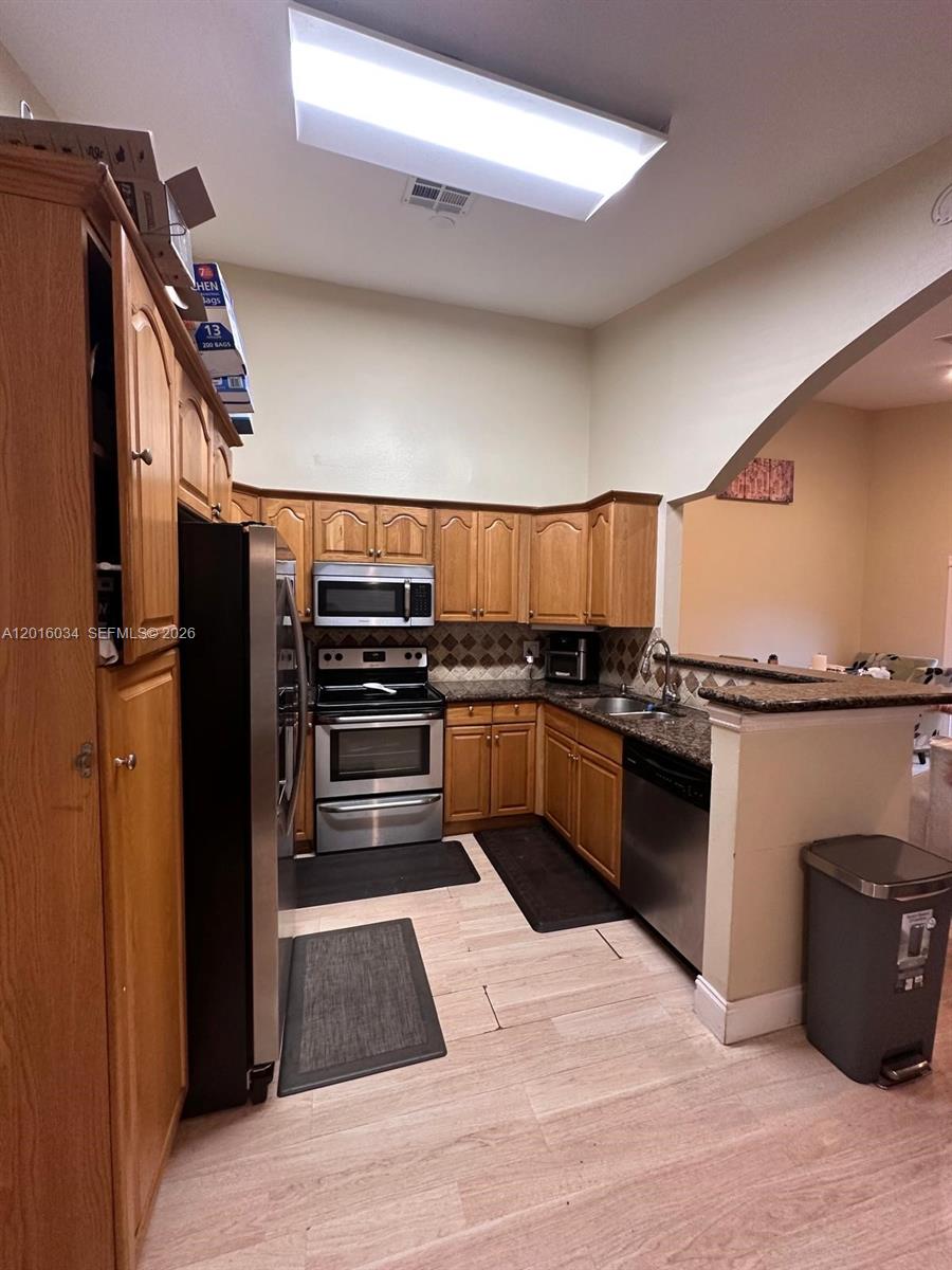 An open-concept living area features light wood-look flooring, white walls, and a kitchen breakfast bar — 11143 E Model Cir E, Boca Raton FL 33428, BOCA RATON, FL