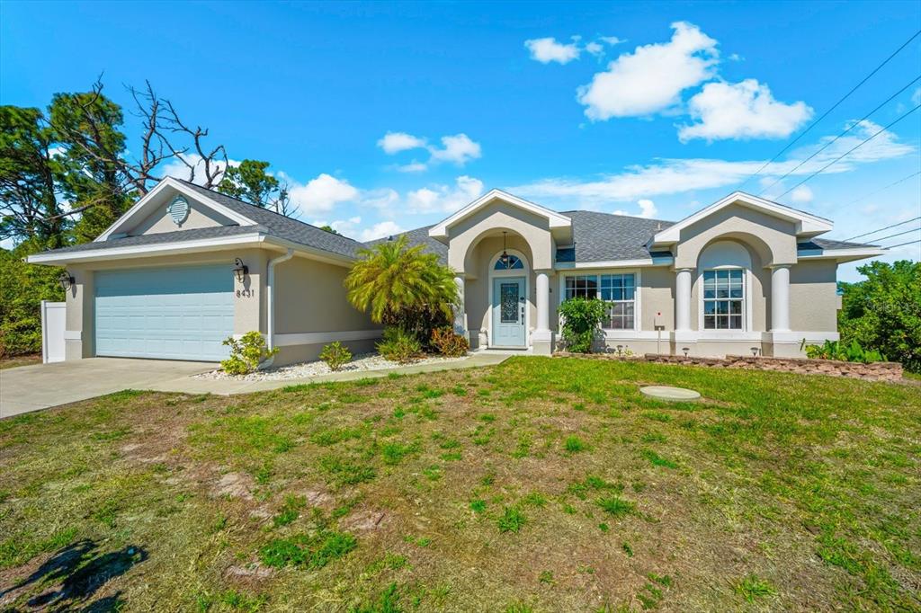 A single-story house with a light-colored stucco exterior, a two-car garage, and a front porch — 8431 WALDREP STREET, PORT CHARLOTTE, FL