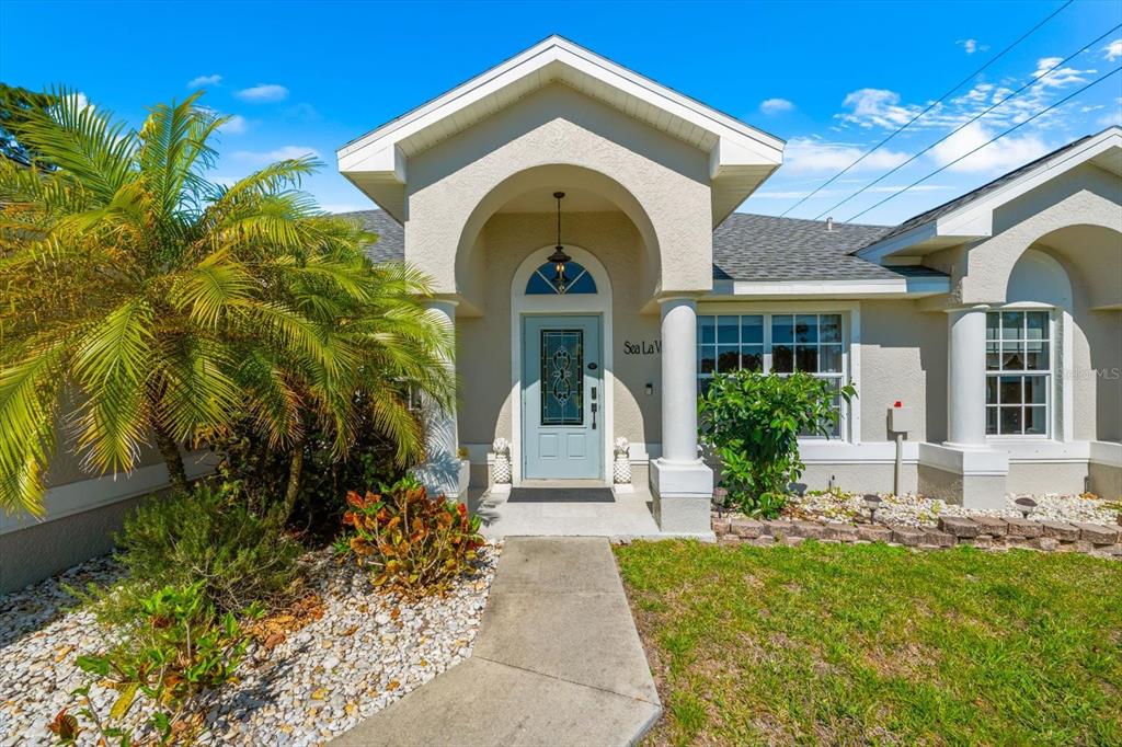 The exterior of a house features a light blue front door under a covered entryway — 8431 WALDREP STREET, PORT CHARLOTTE, FL