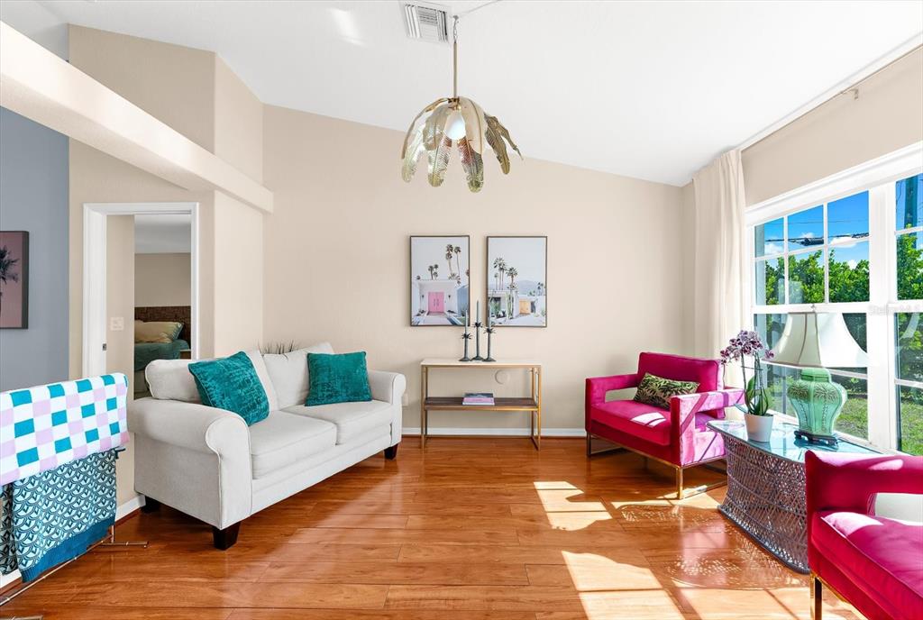 A living room features a white sofa, pink armchairs, a console table, and hardwood floors — 8431 WALDREP STREET, PORT CHARLOTTE, FL