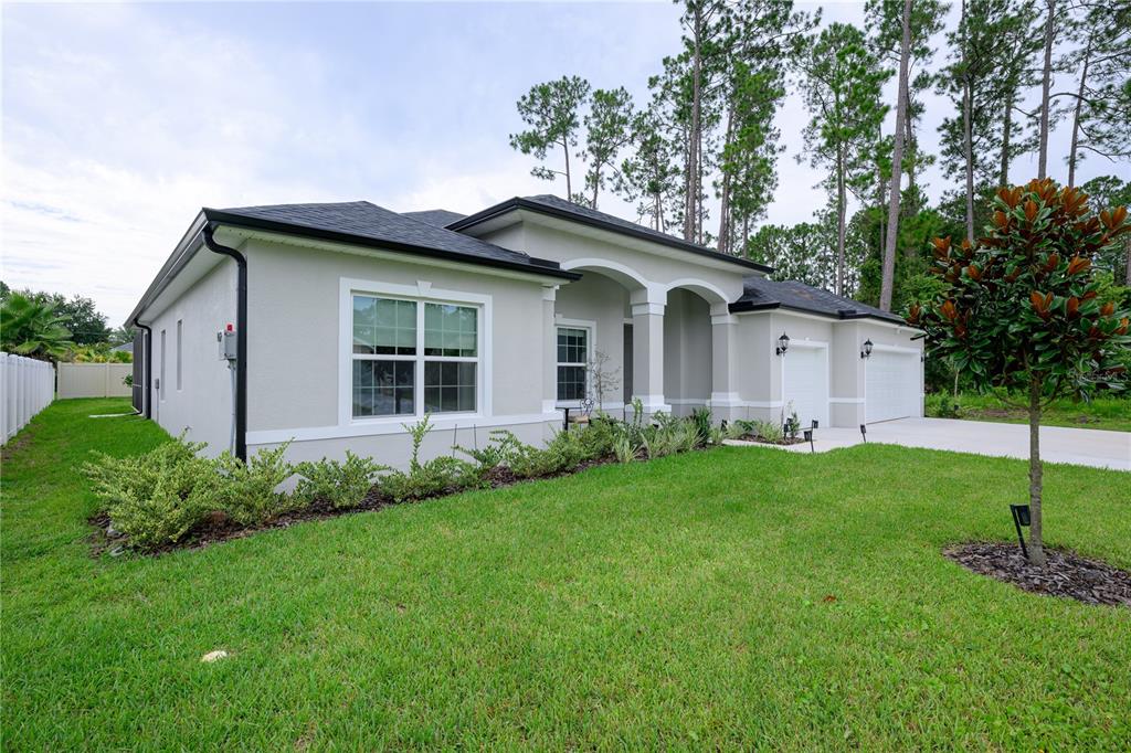 A single-story house with a light gray stucco exterior, arched entryway, and a two-car garage — 25 EDGE LANE, PALM COAST, FL