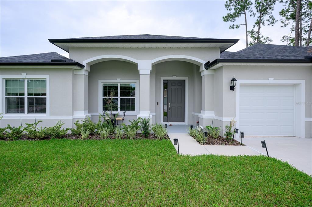 A single-story house with a gray exterior, a covered entryway, and a one-car garage — 25 EDGE LANE, PALM COAST, FL
