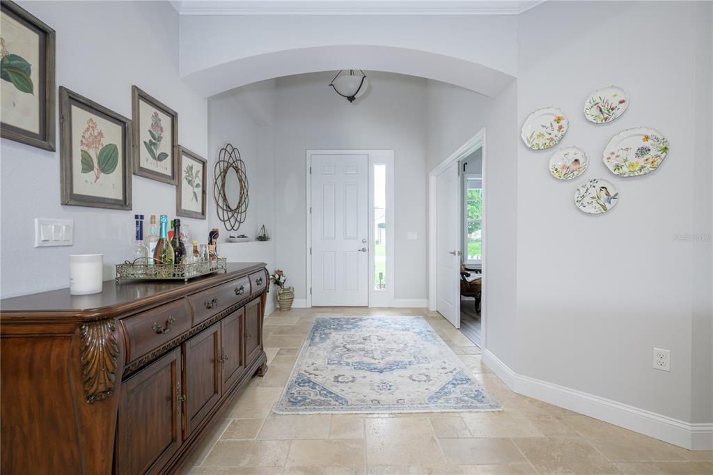 A foyer features a wooden sideboard, a patterned area rug, and decorative wall plates — 25 EDGE LANE, PALM COAST, FL