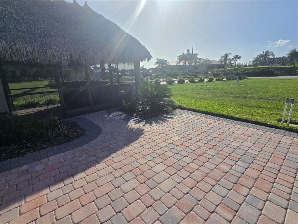 A thatched-roof gazebo sits beside a paved brick patio overlooking a grassy lawn — 3063 WOOD DUCK DRIVE, POLK CITY, FL
