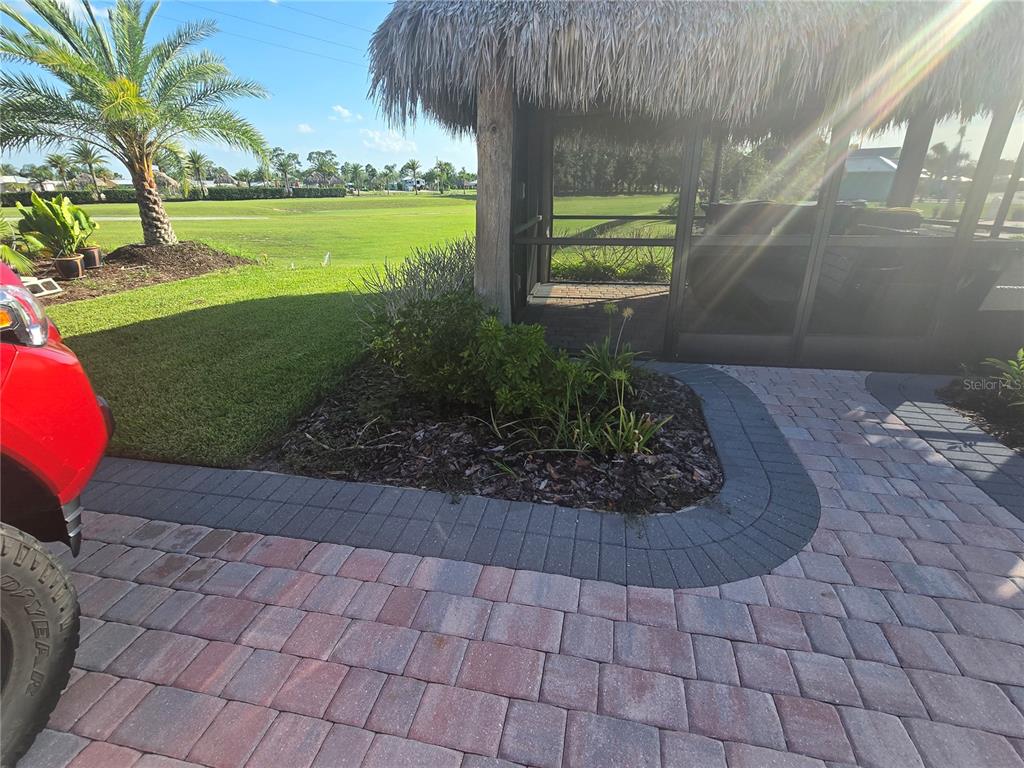 A paved patio area features a thatched-roof gazebo next to a landscaped garden bed — 3063 WOOD DUCK DRIVE, POLK CITY, FL