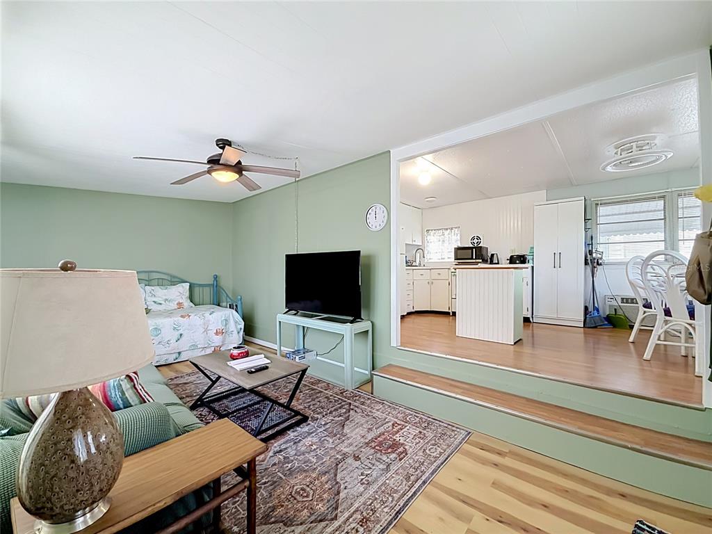 A living room with a daybed and TV leads up a step to a kitchen — 12674 SEMINOLE BOULEVARD UNIT M2, LARGO, FL