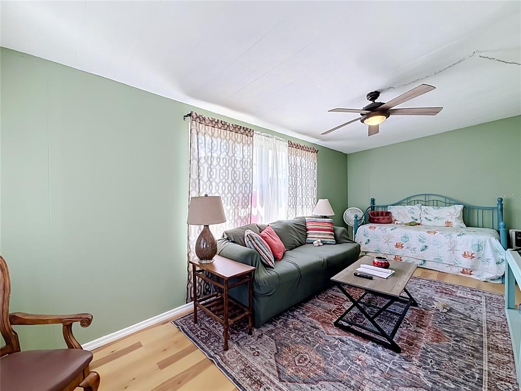 A living room features green walls, a dark sofa, a daybed, and a patterned rug — 12674 SEMINOLE BOULEVARD UNIT M2, LARGO, FL