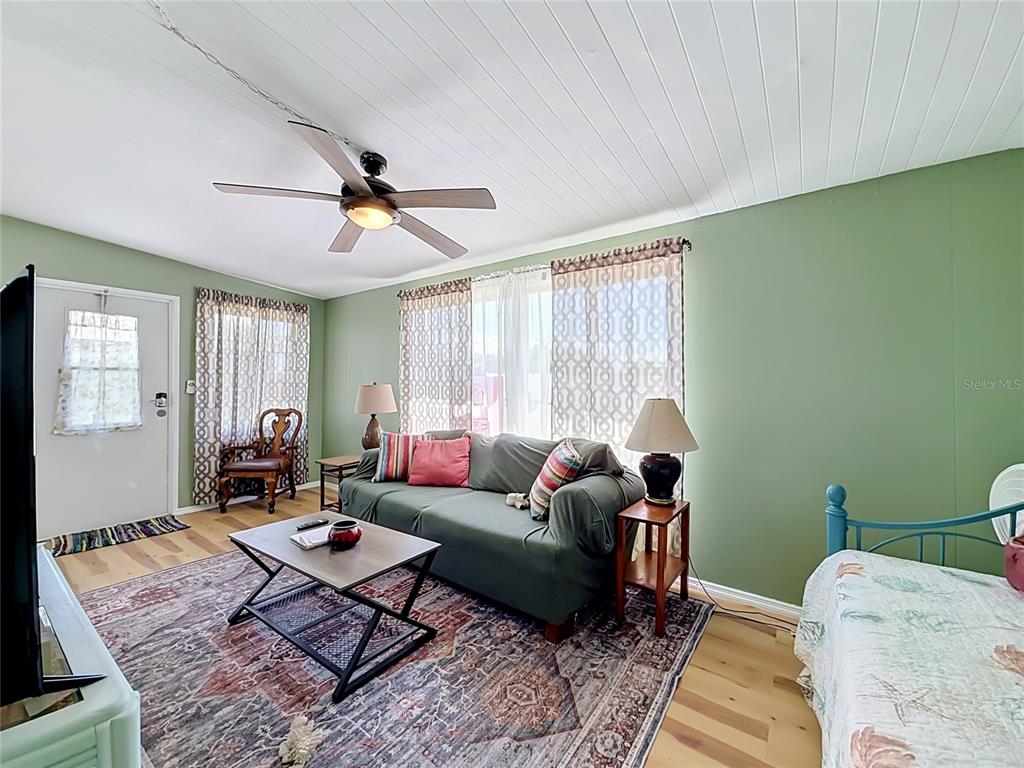 A living room features green walls, a ceiling fan, a sofa, and a patterned rug — 12674 SEMINOLE BOULEVARD UNIT M2, LARGO, FL