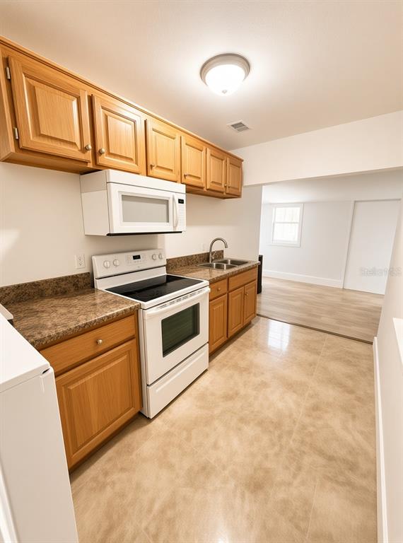 A kitchen features wood cabinets, a white stove, a microwave, and light-colored tile flooring — 1125 13TH AVENUE S, ST PETERSBURG, FL