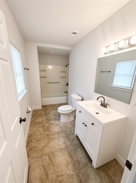 A bathroom features a white vanity, a toilet, and a shower-tub combination with tiled floors — 1125 13TH AVENUE S, ST PETERSBURG, FL