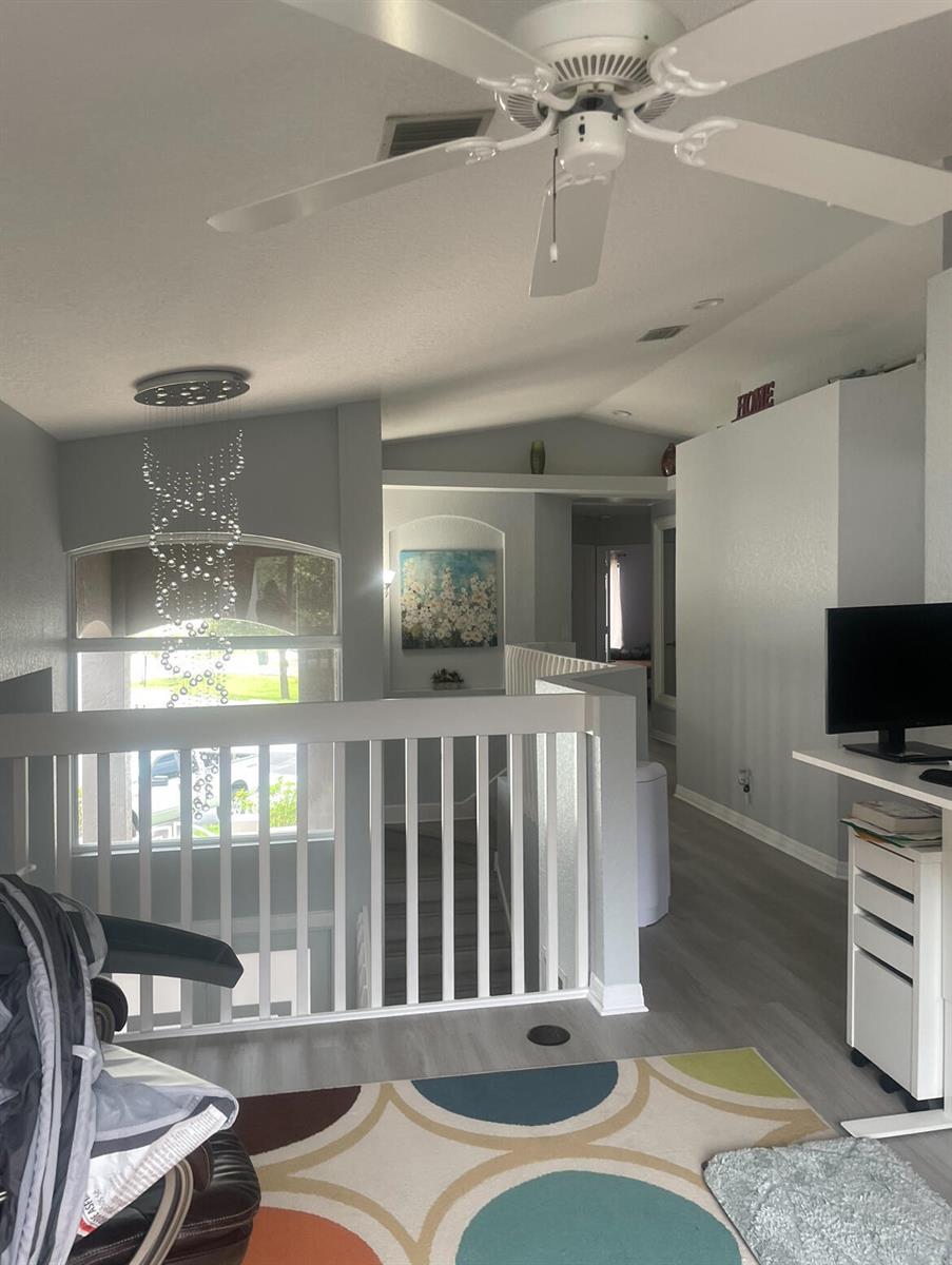 A loft area features a ceiling fan, a crystal chandelier, white railings, and light flooring — 4251 Pine Hollow Circle, FL 33463, FL