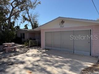 A pink house with a large garage and a concrete driveway under a clear sky — 7127 PENINSULAR DRIVE, NEW PORT RICHEY, FL