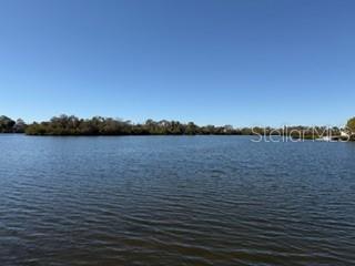 A view of a calm lake with a treeline in the distance under a clear sky — 7127 PENINSULAR DRIVE, NEW PORT RICHEY, FL
