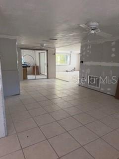 An interior room features light-colored tile flooring, unfinished drywall, and a ceiling fan — 7127 PENINSULAR DRIVE, NEW PORT RICHEY, FL