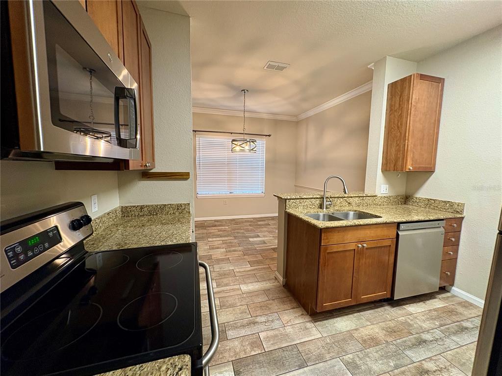 A kitchen with wood cabinets, granite countertops, stainless steel appliances, and tile flooring — 2171 PORTOFINO PLACE UNIT 2714, PALM HARBOR, FL