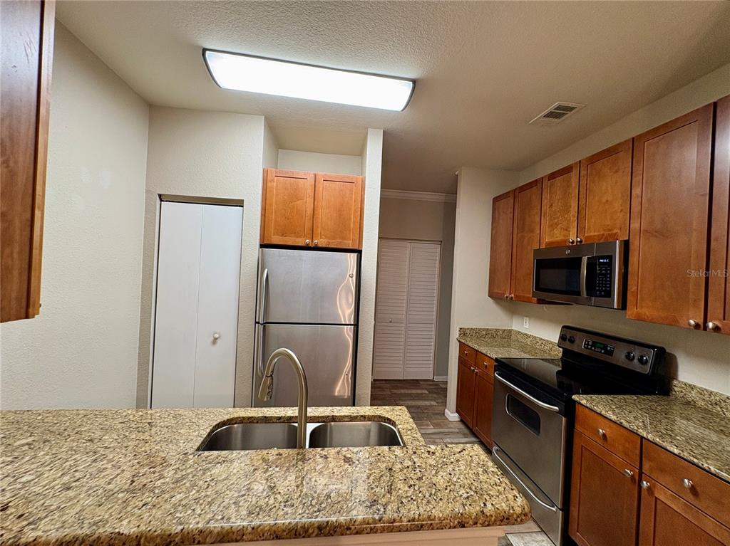 A kitchen features granite countertops, stainless steel appliances, and wood cabinetry — 2171 PORTOFINO PLACE UNIT 2714, PALM HARBOR, FL