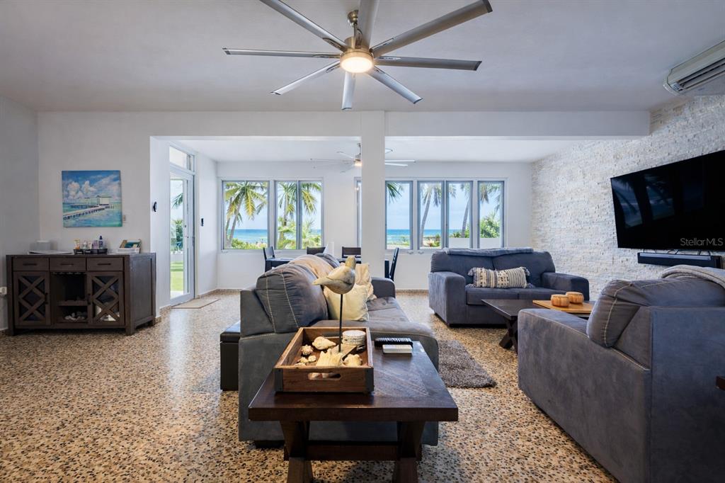 A living room features a stone accent wall, blue sofas, and views of the ocean — STREET NO 3 KM 112 BO. GUARDARRAYA, PATILLAS, PR