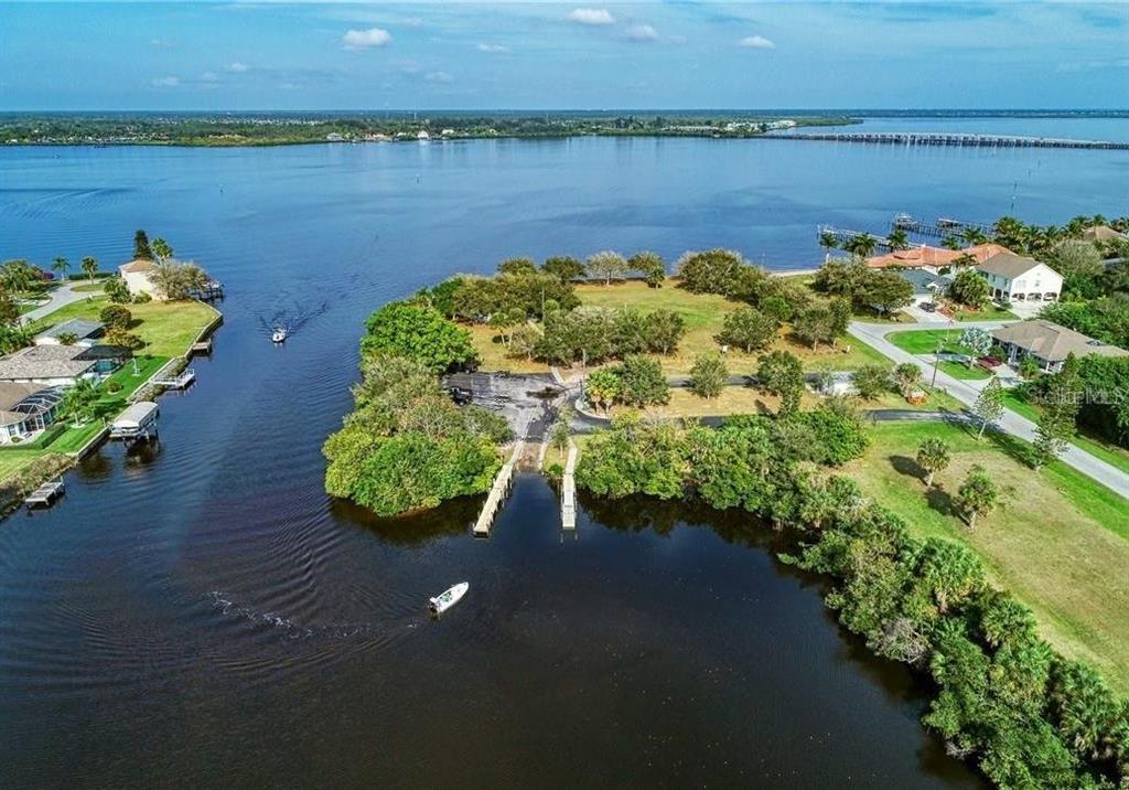 An aerial view shows a boat ramp, a grassy lot, and a waterway with boats — 12342 GABRIEL AVENUE, PORT CHARLOTTE, FL