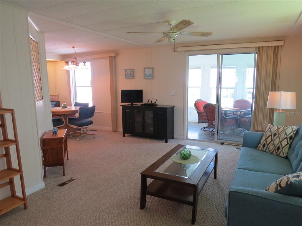 A living room with beige carpet, a blue sofa, a coffee table, and a dining area — 705 BLACKBURN BOULEVARD, NORTH PORT, FL