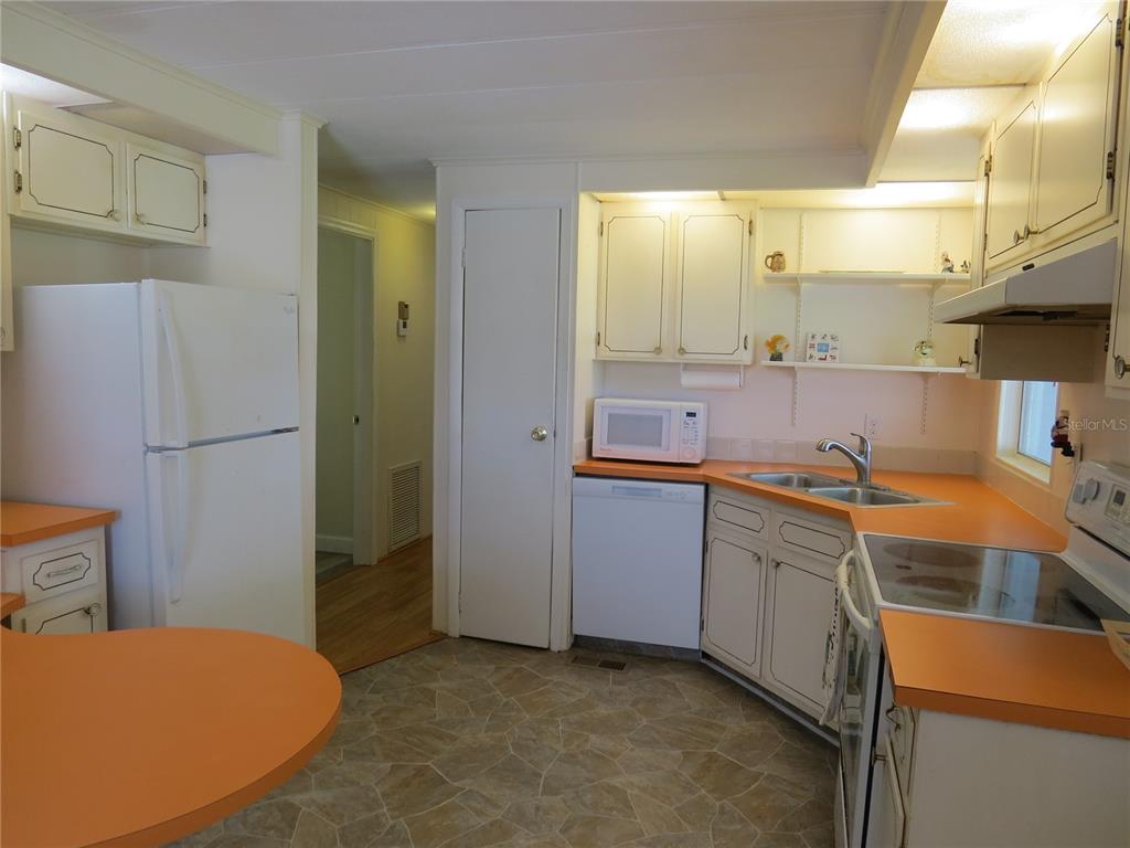A kitchen with white cabinets, orange countertops, a white refrigerator, and a vinyl floor — 705 BLACKBURN BOULEVARD, NORTH PORT, FL