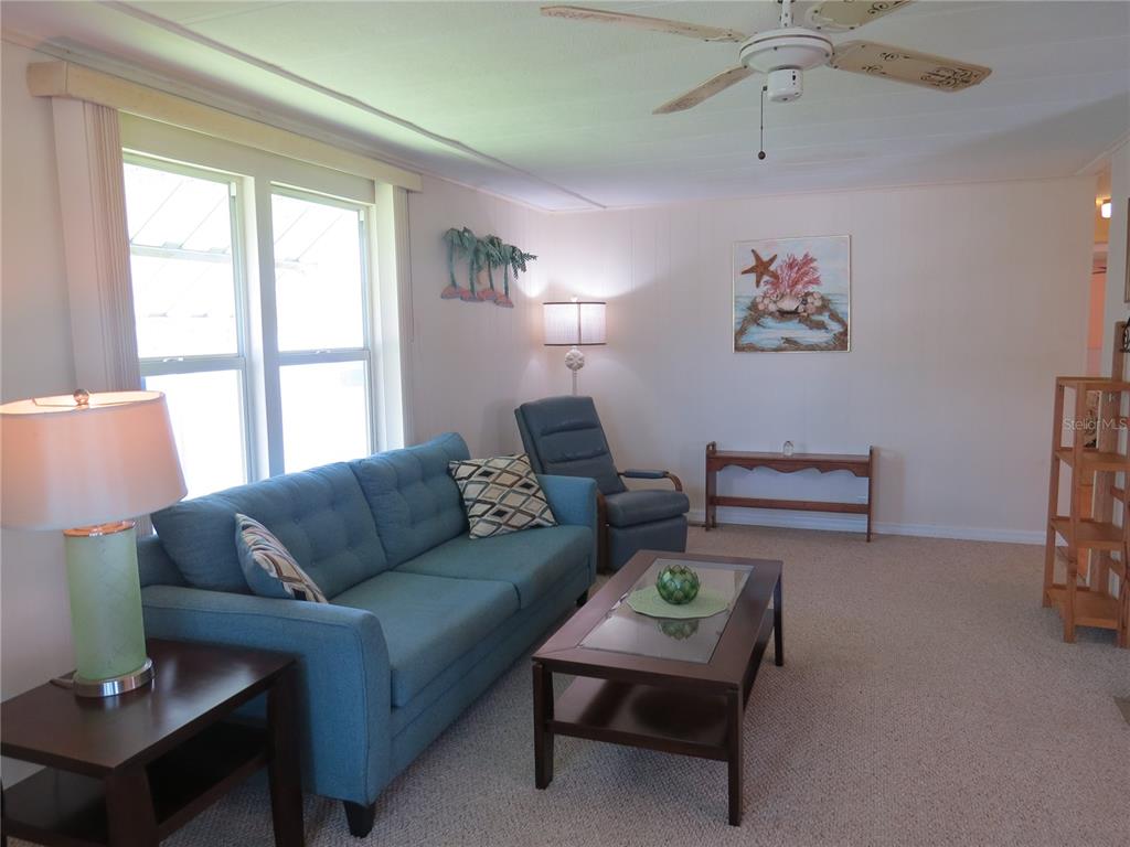 A living room features a blue sofa, a coffee table, a recliner, and a ceiling fan — 705 BLACKBURN BOULEVARD, NORTH PORT, FL