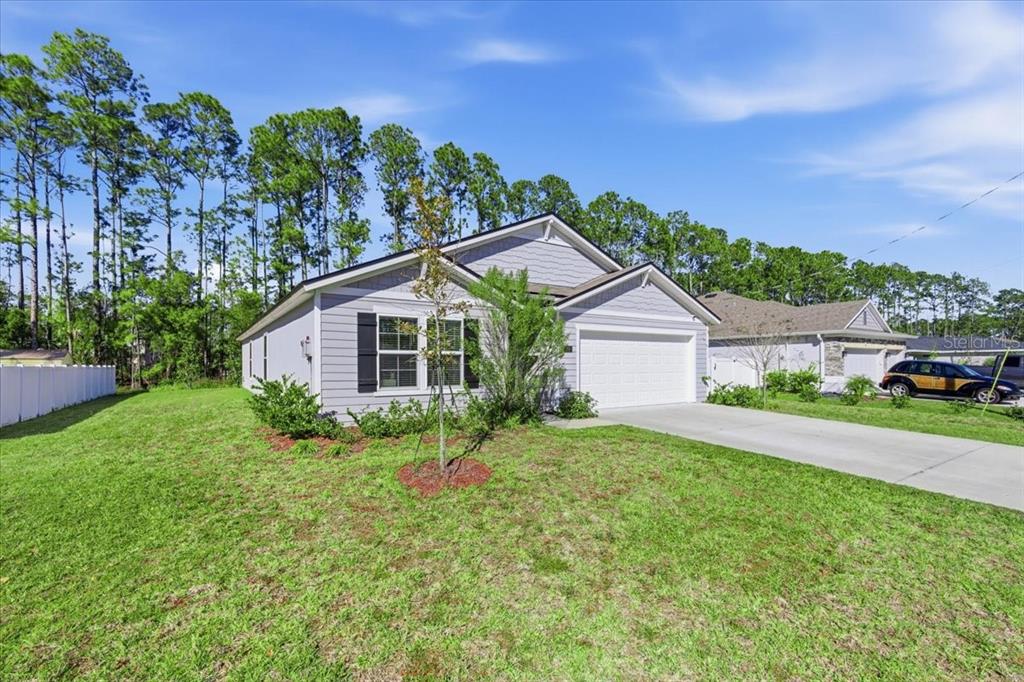 A single-story house with light gray siding, a two-car garage, and a grassy front yard — 100 RYAN DRIVE, PALM COAST, FL