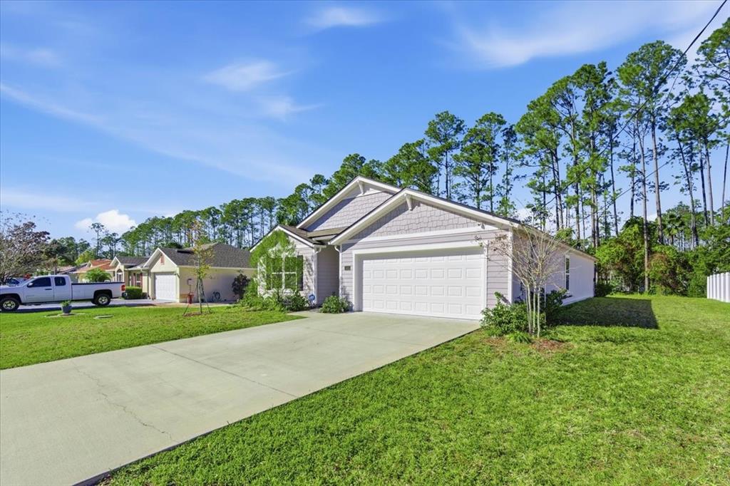 A single-story house with a two-car garage, light siding, and a concrete driveway — 100 RYAN DRIVE, PALM COAST, FL