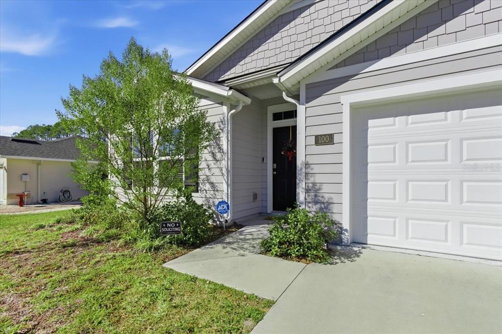 The exterior of a single-story house features light gray siding, a garage, and a front entrance — 100 RYAN DRIVE, PALM COAST, FL