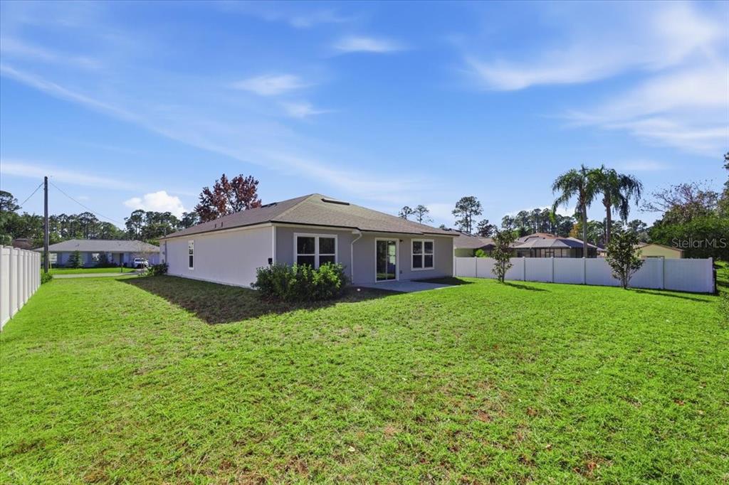 A view of the backyard and the rear exterior of a single-story house — 100 RYAN DRIVE, PALM COAST, FL