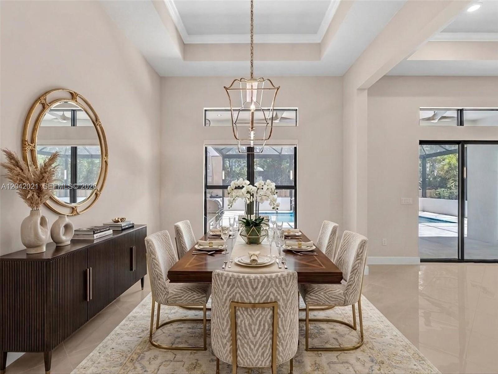 A dining room features a wooden table, upholstered chairs, a gold chandelier, and a sideboard — 7680 Cavern Ln, Parkland FL 33067, PARKLAND, FL
